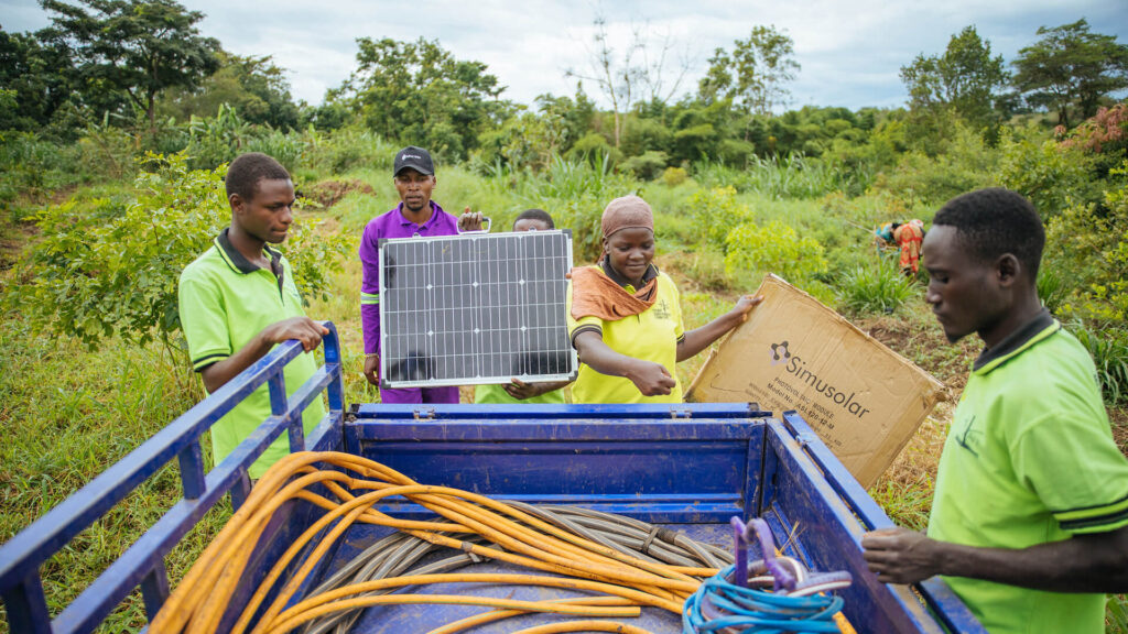 People in a field with Simusolar solar components in a truck bed.