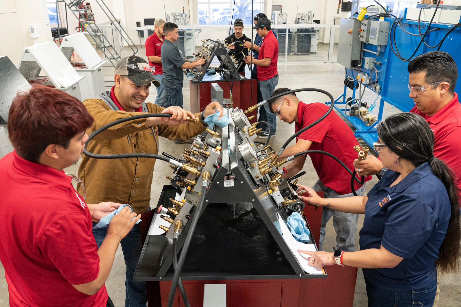 Students standing over and tinkering with robotics and hydraulics machines while learning at St. Philips College.