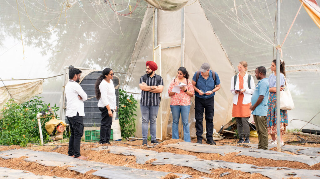 Autodesk volunteers inside a greenhouse with members of the Kheyti team in India.