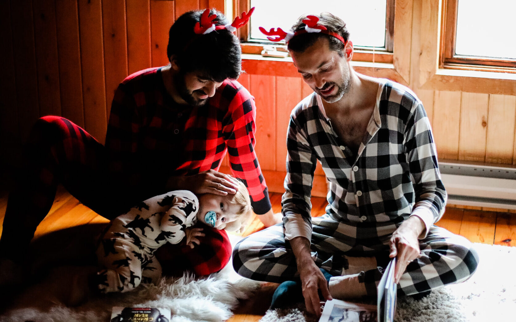 Autodesk employee Adrien Dixneuf sits on the ground with his husband, reading a book to their son.