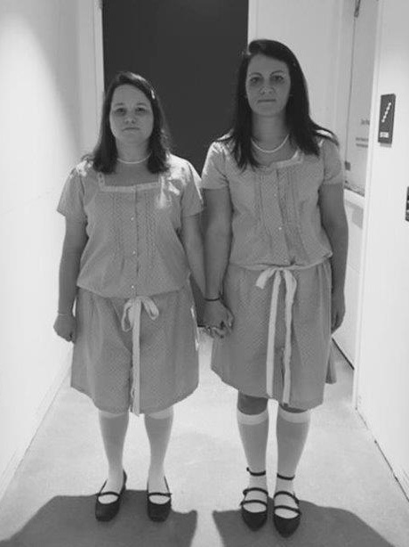 Colleen Lucksinger and Shona McMoran stand in a hallway dressed as the twins from the movie "The Shining" for Halloween.