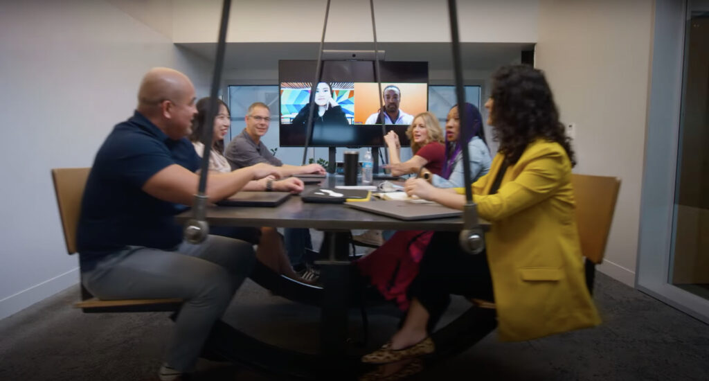 Six Autodesk employees meet while sitting at a swinging desk