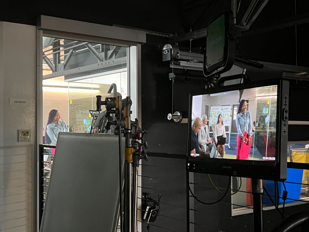 Behind the scenes of the video shoot, a monitor shows how the scene appears on camera