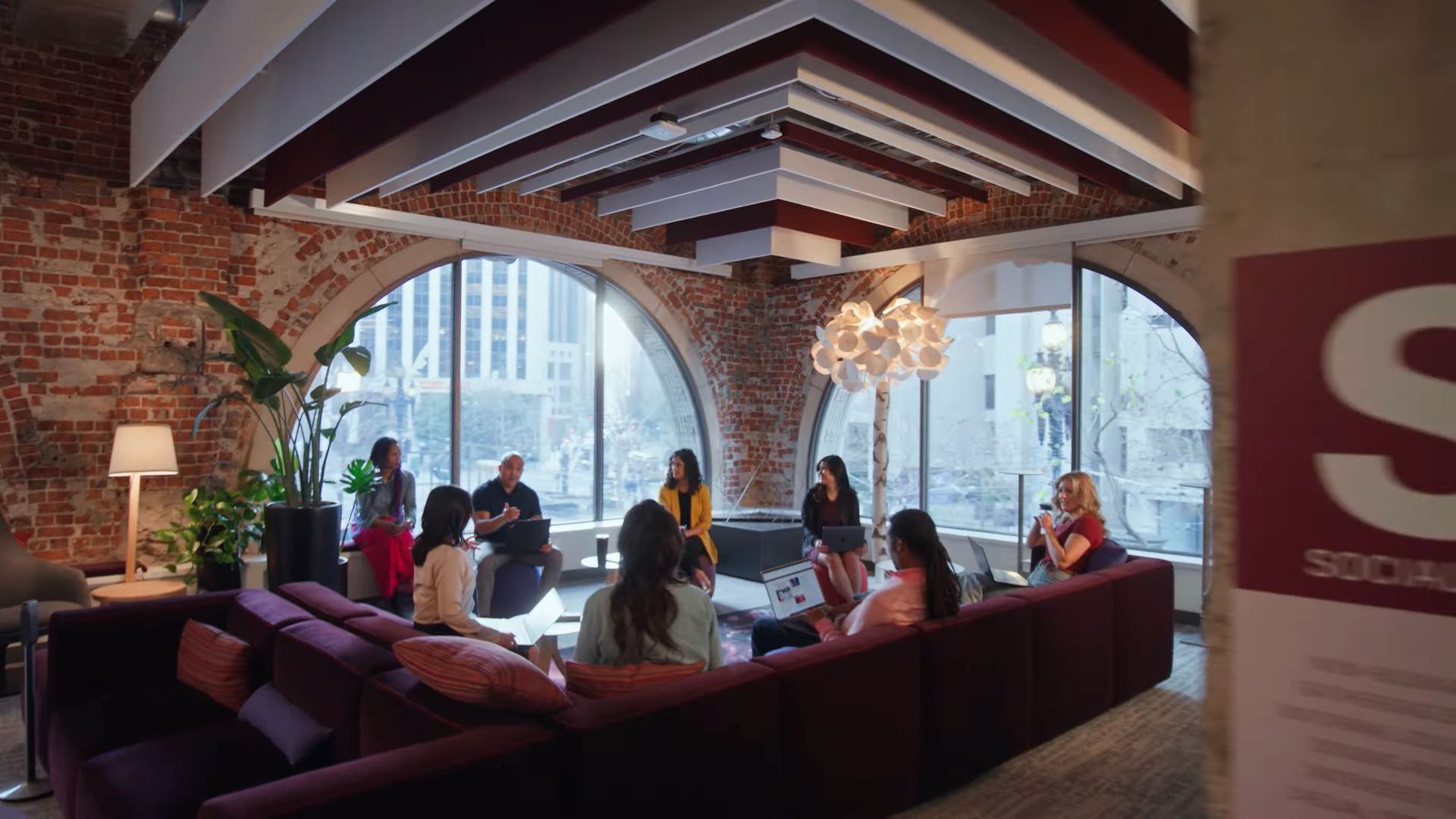 Eight Autodesk employees talk to each other while sitting on a purple sectional couch