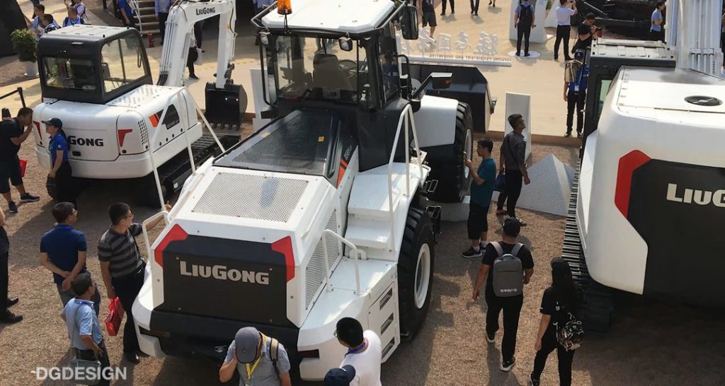 Photograph of construction vehicles at construction exposition in Las Vegas. People standing around vehicles looking at them and talking.