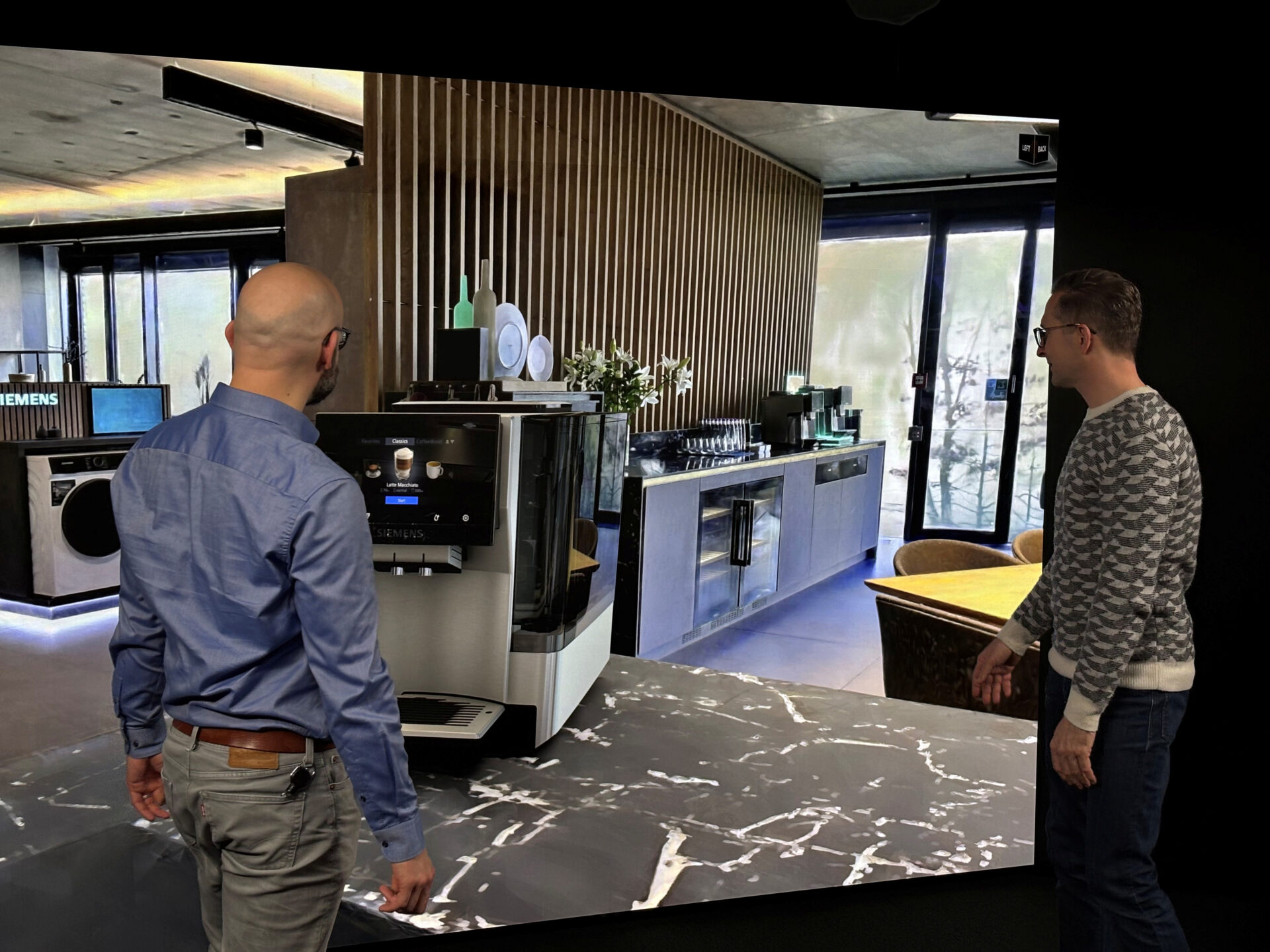 Two designers review a product in a Gaussian splat environment on a powerwall using Autodesk VRED.