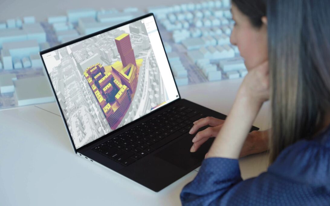 A woman working on a 3d rendering of a building in a city.