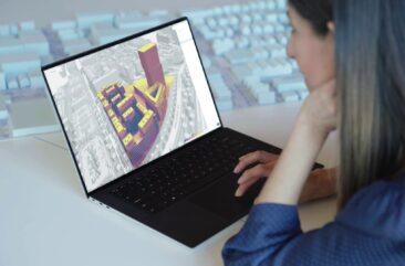 A woman working on a 3d rendering of a building in a city.