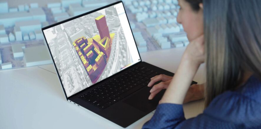 A woman working on a 3d rendering of a building in a city.