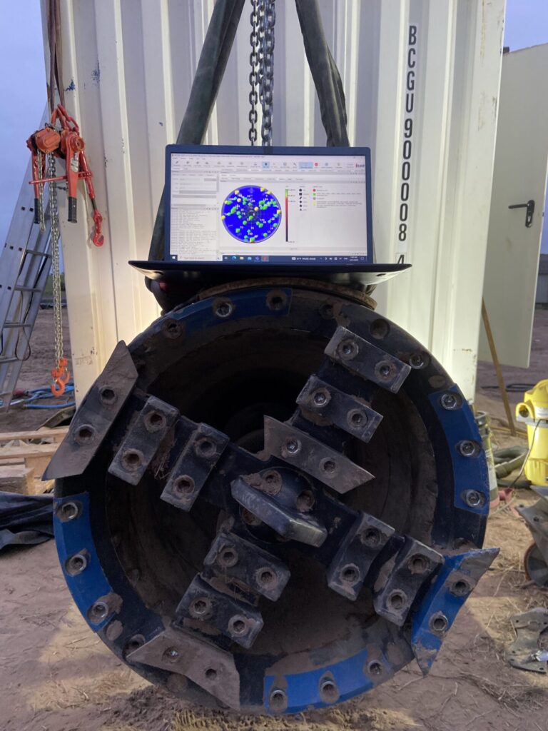 Photo of tunnel boring machine part with Autodesk Fusion 360 design on a laptop next to it.