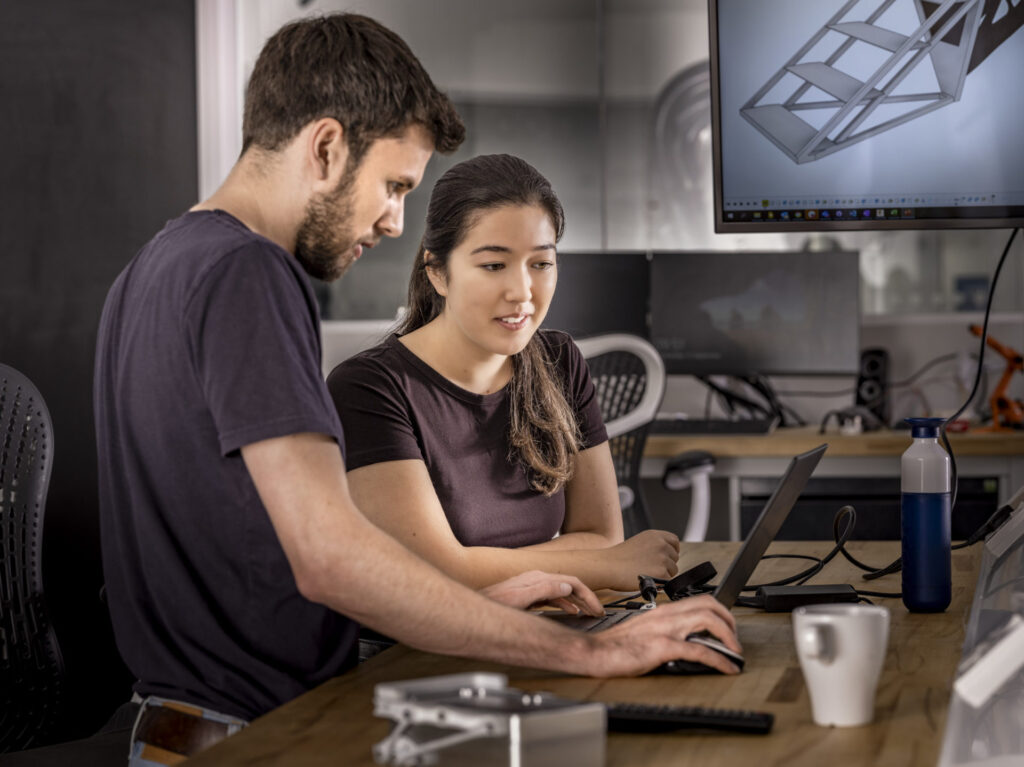 Two people looking at laptop in Computer-aided Manufacturing (CAM) lab.
