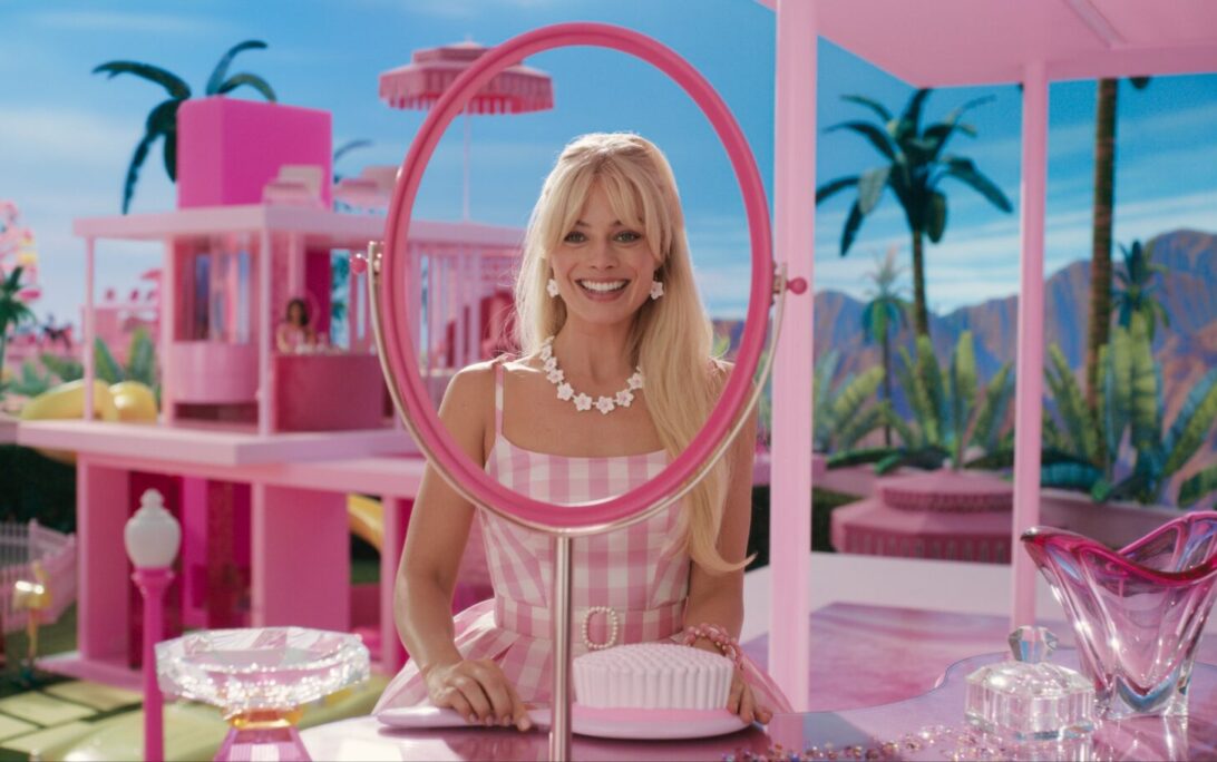 Live-action Barbie played by Margo Robbie looking at a mirror smiling