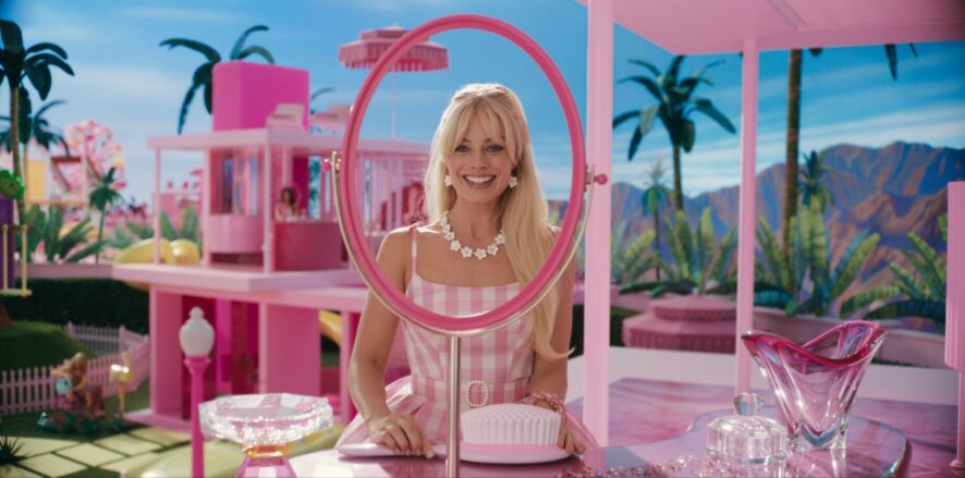 Live-action Barbie played by Margo Robbie looking at a mirror smiling