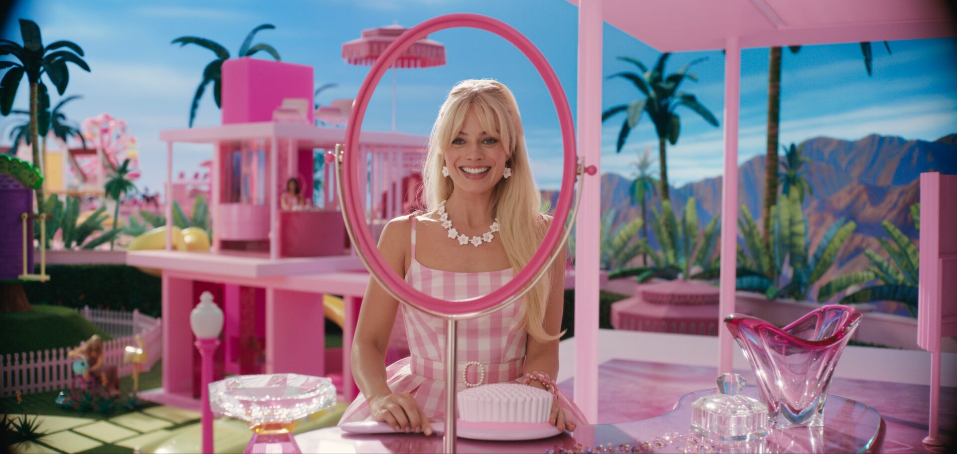 Live-action Barbie played by Margo Robbie looking at a mirror smiling
