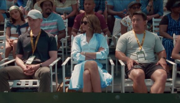 Tashi (portrayed by Zendaya), is seated amongst an audience of tennis fanatics with her arms crossed.