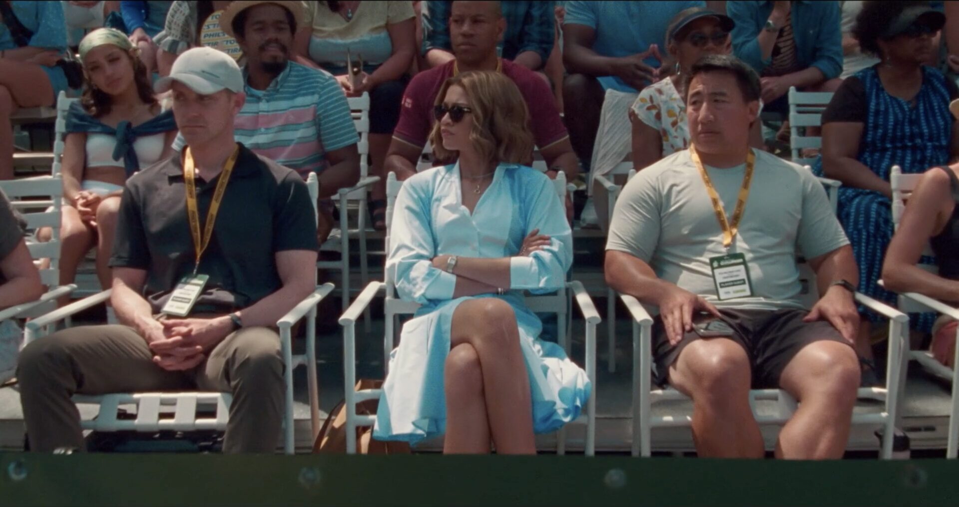 Tashi (portrayed by Zendaya), is seated amongst an audience of tennis fanatics with her arms crossed.