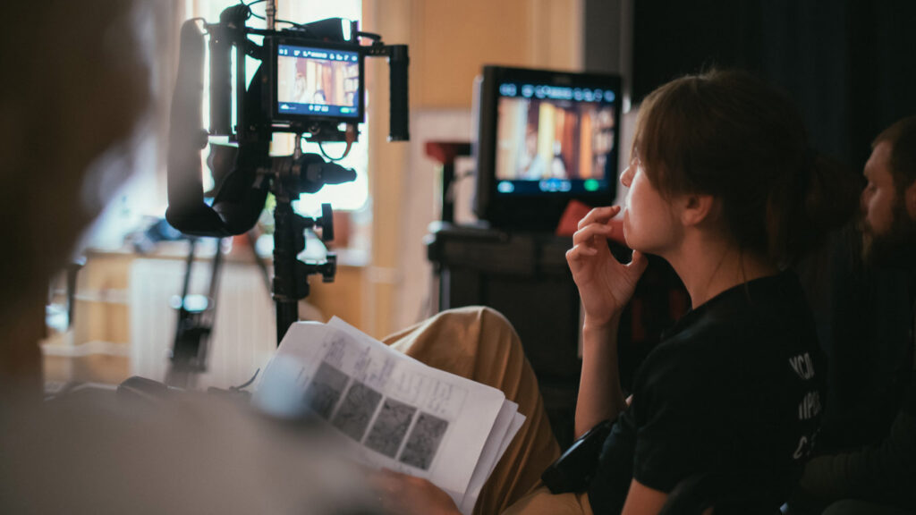 A director or a production looks a a monitor while holding printed pages of a storyboard